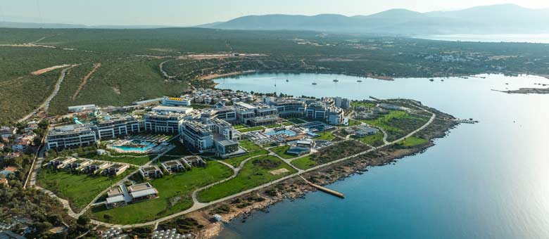 An aerial view of the Anda Barut Collection Hotel showing the landscaped grounds alongside the sandy beach and seafront with calm clear water.