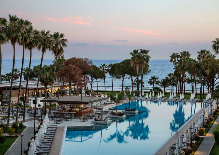 A line of palm trees separate the beach from the hotel grounds and swimming pools at Acanthus Cennet Barut Collection