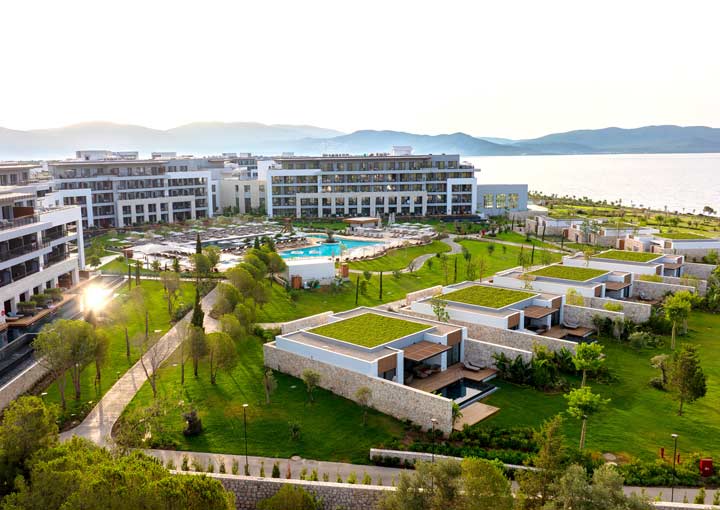 Looking across the resort in early morning light at Anda Barut Collection with the sea shimmering in the background with sun light reflecting over the still blue water