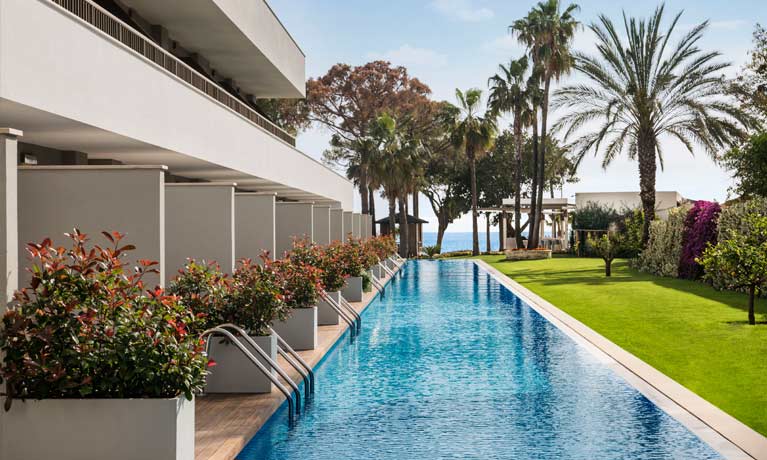 Swim-up hotel rooms at a Barut Collection hotel surounded by landscaped gardens and the beach beyond