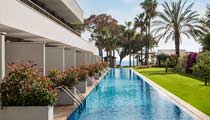 Swim-up hotel rooms at a Barut Collection hotel surounded by landscaped gardens and the beach beyond