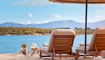 Children play on a sandy beach beside their parents sun loungers on a warm sunny day by the sea