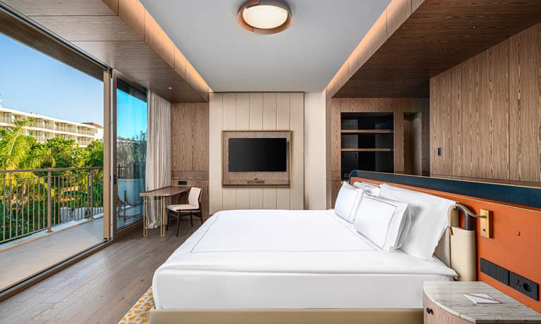 A spacious and modern bedroom with floor to ceiling sliding glass doors opened up to a large terrace balcony area