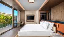 A spacious and modern bedroom with floor to ceiling sliding glass doors opened up to a large terrace balcony area