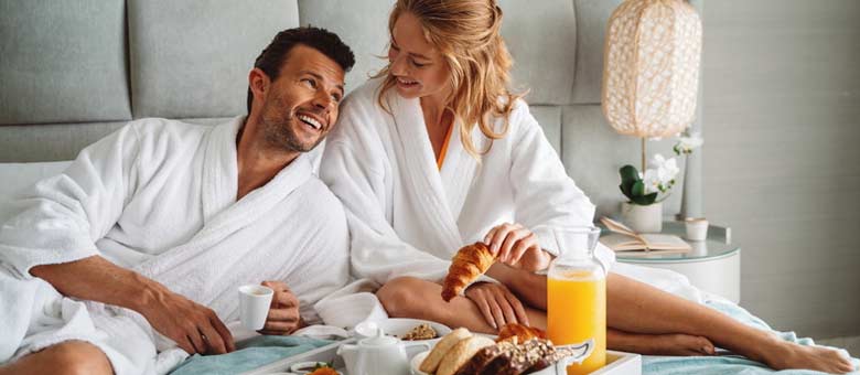 A couple enjoy the privileges of a deluxe suite with a sumptious breakfast delivered to their suite.