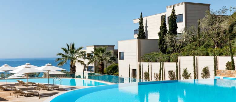 A quiet area at Ikos Oceania in Halkidiki, featuring two swimming pools perfect for couples to relax and unwind while looking over the beach and sea