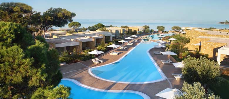 Three swimming pools can be seen stretching from the foreground of Ikos Olivia hotel down to the beach in Halkidiki, on a clear blue day in the sunshine.