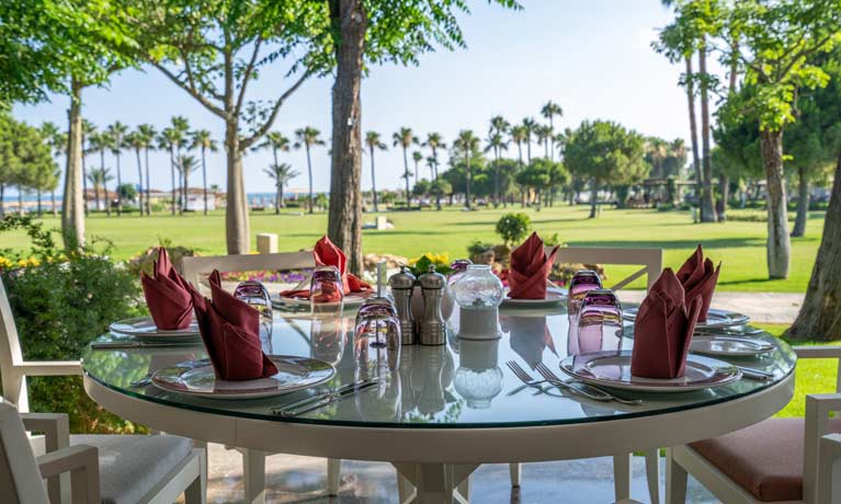 A table is set for lunch in front of picturesque views over the beach to the calm blue sea beyond