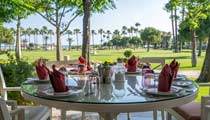 A table is set for lunch in front of picturesque views over the beach to the calm blue sea beyond