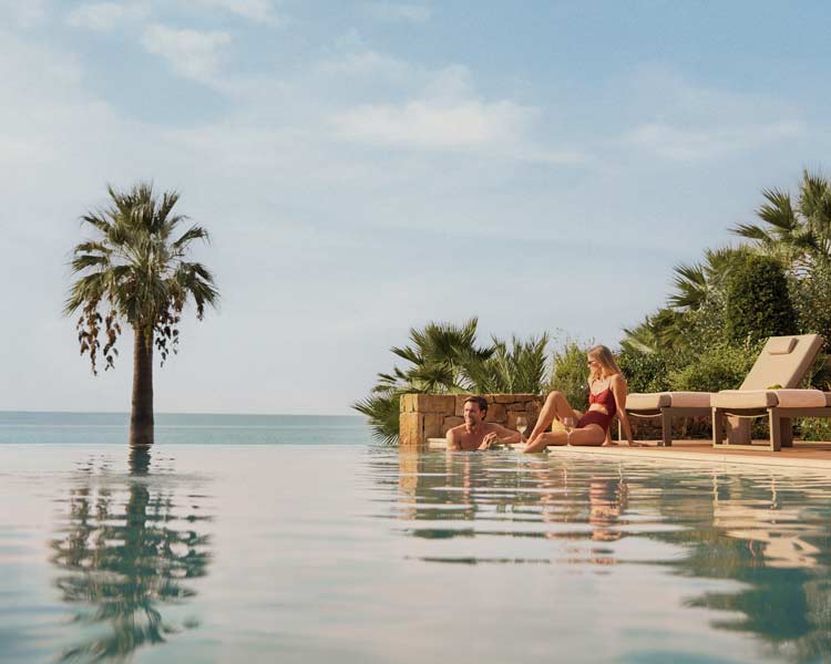 A couple soak up the summer sunshine beside one of many swimming pools at Sani Resort