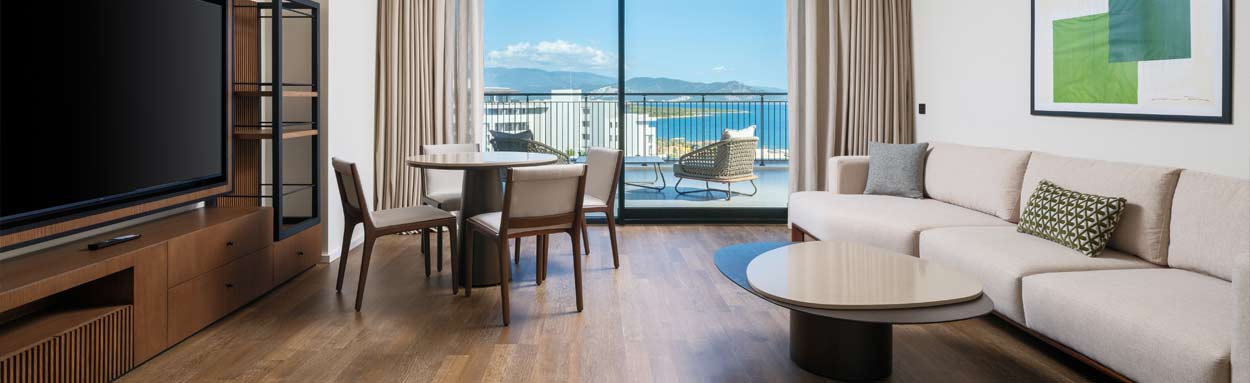 An example of the high standard accommodation at Anda Barut Collection, looking out the large patio windows with the sea beyond, the room is spacious and furnished with contemporary decor and facilities